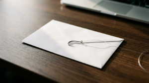 Fishing hook resting on a paper envelope, illustrating how phishing emails try to hook their targets